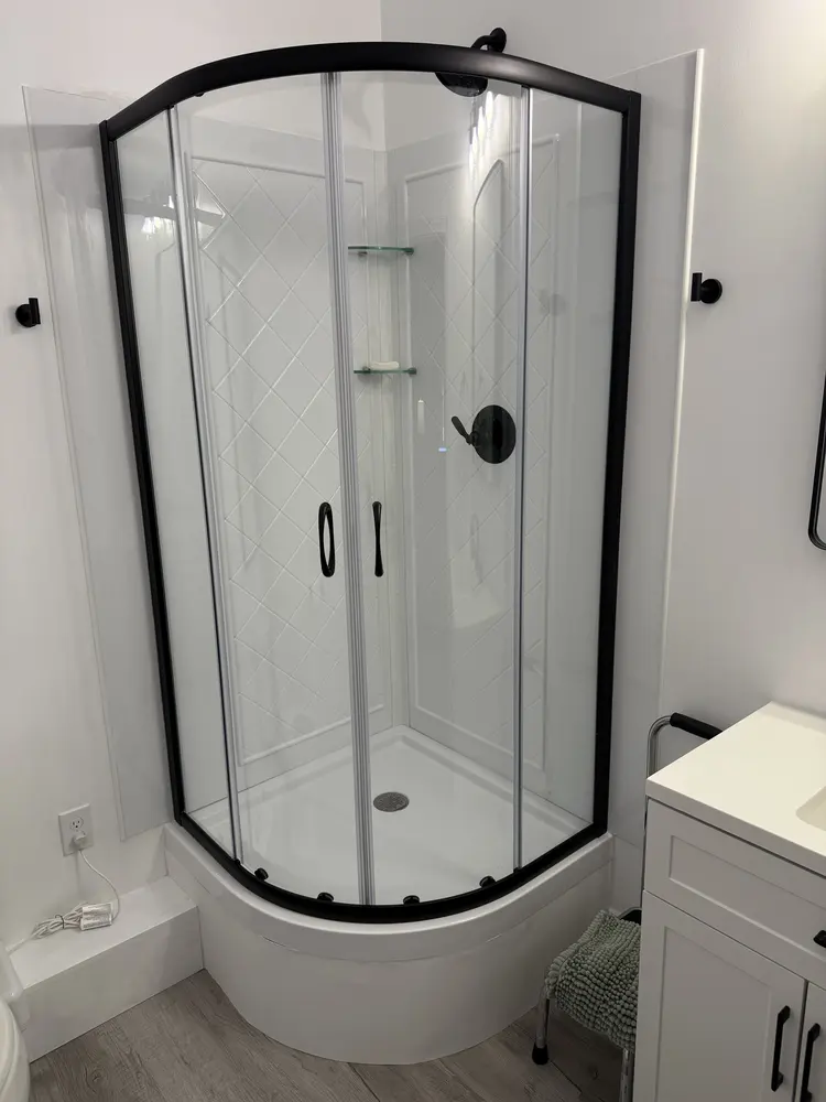 Corner shower with a black frame and matching valve trim
